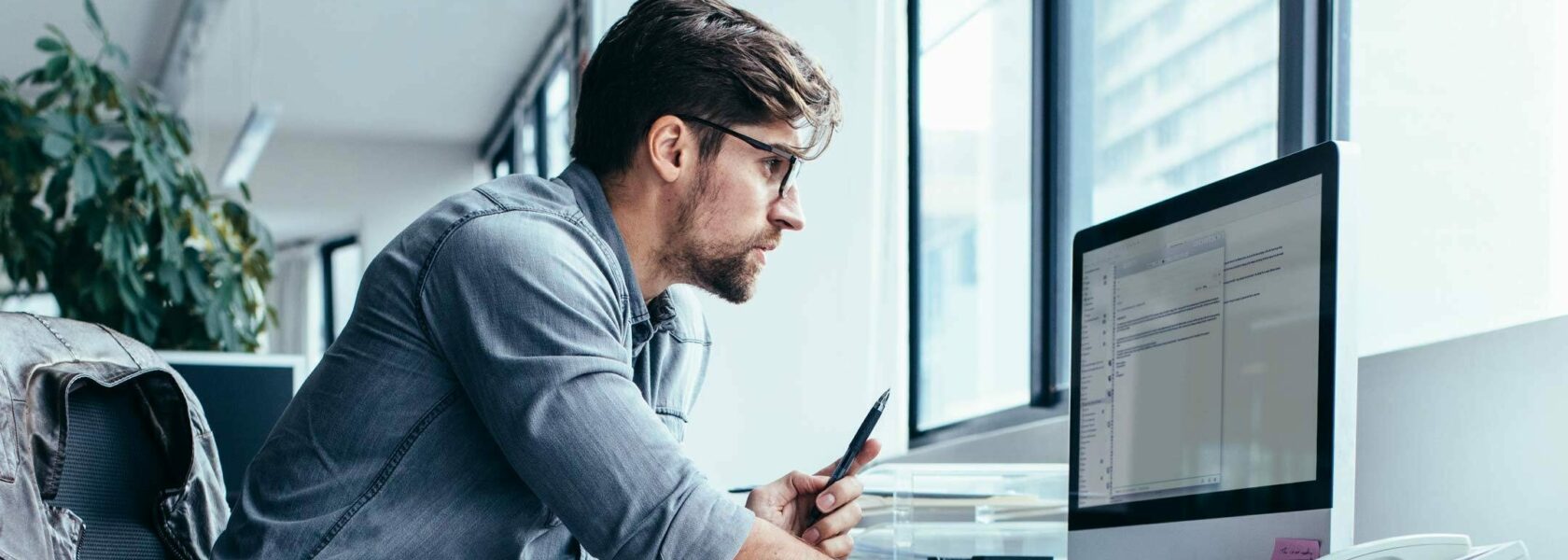 Un collaborateur consultant ses emails sur un iMac dans un open space