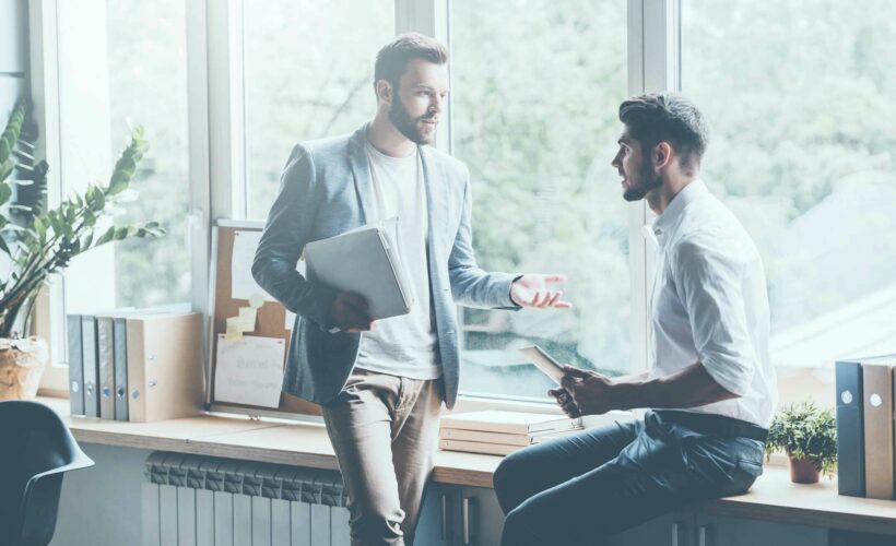 Deux collègues ayant une discussion informelle à côté d’une fenêtre